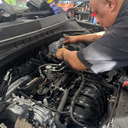 AutoPlus technician servicing the engine bay and A/C components of a vehicle